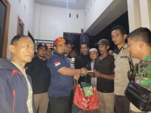 Pj Bupati Aceh Besar Muhammad Iswano SSTP MSi sedang menyerahkan bantuan masa panik untuk korban terdampak kebakaran di Meunasah Papeun. Foto Dinsos Abes.